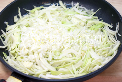 В сковороду налить немного масла и выложить капусту. Добавить мелко нашинкованный лук и готовить на среднем огне 12-15 минут, помешивая