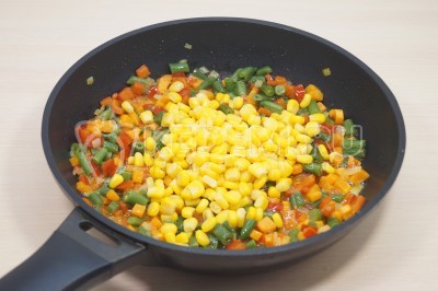 Добавить 100 грамм консервированной кукурузы. Перемешать и готовить еще 3-4 минуты.