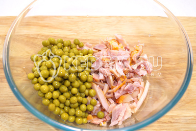 В миску сложить мелко нарезанное куриное мясо и зеленый горошек.