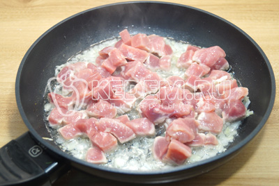 В сковороду с луком добавить кубиками нарезанное мясо. Обжарить 3-5 минут.