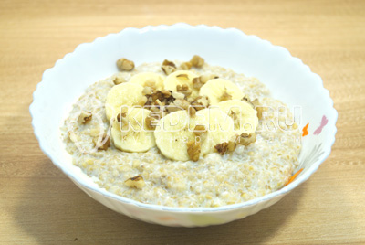На кашу выложить банан и орехи. Сахар добавить по вкусу.