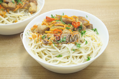 Выложить порцию спагетти. Добавить мясо с овощами, украсить зеленью.
