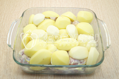 Картофель очистить, нарезать на половинки и выложить в форму на курицу.