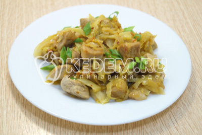 Выложить тушеное мясо с капустой на блюдо и посыпать нашинкованным зеленым луком.