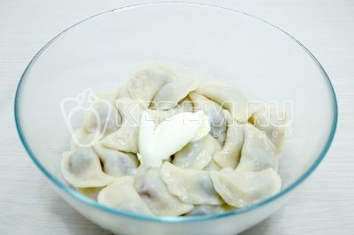 Готовые вареники выложить шумовкой в миску и заправить 1 столовой ложкой сливочного масла.