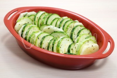 Смазать форму сливочным маслом, выложить кружочки картофеля и кабачка чередуя.