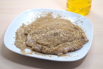 Хорошо запанировать кусочки куриного филе в панировочных сухарях.