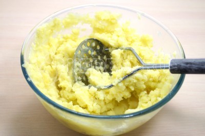 Выложить картофель в миску и размять толкушкой.