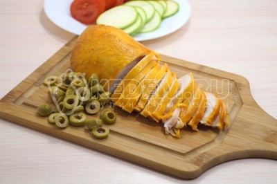Копченую куриную грудку нарезать тонкими ломтиками, оливки нарезать колечками.