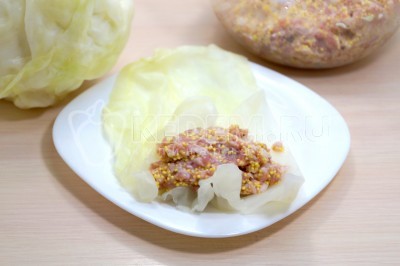 На тонкий кусочек капустного листа выложить 1-2 соловые ложки начинки.
