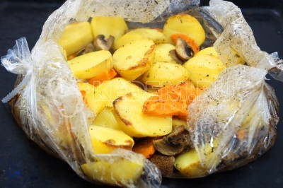 Вынуть картофель с грибами из духовки. Разрезать пакет и выпустить пар.
