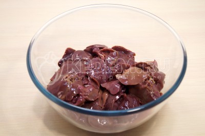 Чтобы приготовить куриную печень с луком и морковью на сковороде, нужно в большую миску выложить 500 грамм куриной печени, при необходимости предварительно разморозить.