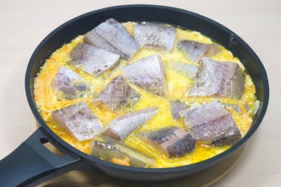 Выложить кусочки минтая в сковороду со сметанным соусом.