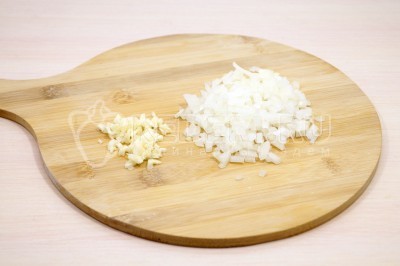 Чтобы приготовить макароны с курицей и шпинатом нужно луковицу мелко нашинковать. 2 зубчика чеснока измельчить.