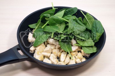 В сковороду с курицей добавить 1/2 чайной ложки соли и шпинат.