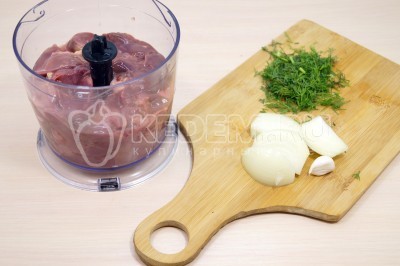 Чтобы приготовить печеночные оладьи из куриной печени нужно 400 грамм куриной печени сложить в чашу для блендера. Добавить 1 нарезанную луковицу, 1 зубчик чеснока и 1 небольшой нарезанный пучок зелени укропа.