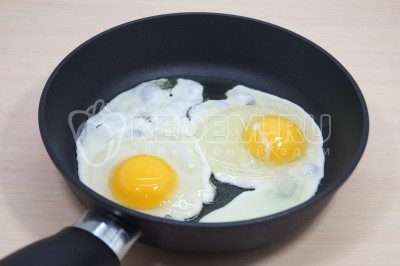 Добавить 2 яйца и приготовить глазунью с жидким желтком. Посолить по вкусу.