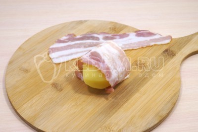 Картофель вынуть из кастрюли и остудить. Обвернуть каждую картофелину полоской бекона.