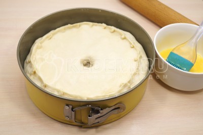 Меньшую часть теста для курника раскатать в круг. Выложить в форму сверху начинки и защипнуть края теста. Сделать в центре отверстие для выхода пара. Смазать взбитым желтком с 1 столовой ложкой молока. Выпекать курник в разогретой до 170 градусов Цельсия духовке 40-45 минут. <i>Приятного аппетита!</i>