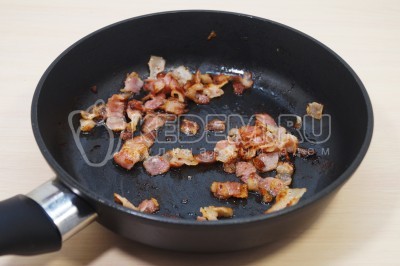 На сухой сковороде обжарить кусочки бекона до хрустящей корочки.