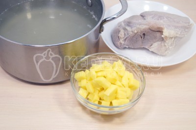 Бульон процедить. Луковицу из бульона выкинуть. Мясо остудить и нарезать кубиками. В бульон добавить 2 кубиками нарезанные картофелины. Варить 5-7 минут.