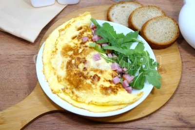 Омлет-конверт с ветчиной и сыром готов. Выложить на блюдо и подавать с зеленью. Можно подавать к столу.