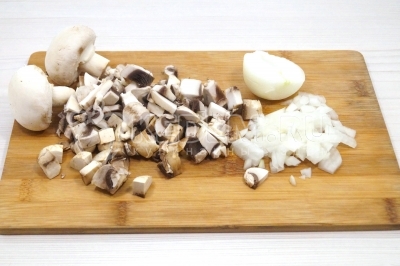 Чтобы приготовить гречку с грибами и луком, нужно 150 грамм свежих грибов шампиньонов нарезать небольшими кубиками. Луковицу нарезать небольшим кубиком.