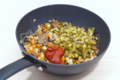 Добавить нарезанные соленые огурцы и 1 столовую ложку томатной пасты. Готовить 3-4 минуты.