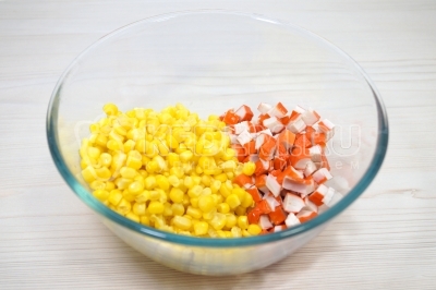 В миске смешать кубиком нарезанные 200 грамм крабовых палочек и 1 банку консервированной кукурузы.