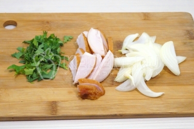 Чтобы приготовить яичницу с курицей, нужно 1-2 веточки зелени петрушки мелко нашинковать. Ломтиками нарезать 50 грамм копченого куриного филе и полукольцами нарезать четверть луковицы.