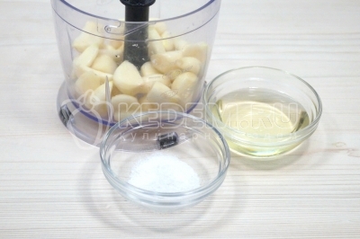 Переложить зубчики чеснока в чашу блендера. Добавить 4 столовые ложки подсолнечного масла и 1/2 чайной ложки соли.