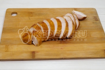 Чтобы приготовить новогодний салат с фасолью и копченым куриным филе «Бобовый карнавал», нужно 200 грамм копченого куриного филе нарезать небольшими кубиками.