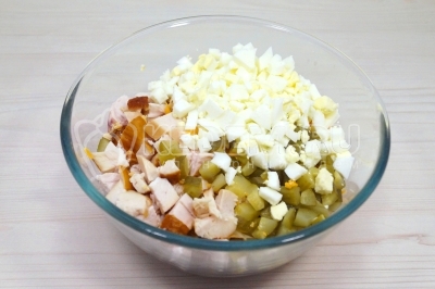 Добавить в миску кубиком нарезанные отварные яйца и 2 маринованных огурца.