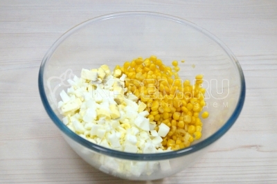 В большой миске смешать кубиками нарезанные отварные яйца и 200 грамм консервированной кукурузы.