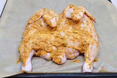 Смазать курицу с двух сторон и выложить на противень грудкой вниз. Оставить на 20-30 минут мариноваться.