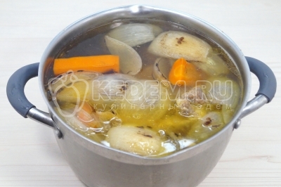 Добавить овощи в кастрюлю с костями. Влить 3-3,5 литра воды. Варить до закипания. Снять накипь. Убавить огонь и варить бульон 2 часа.