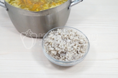 Добавить в кастрюлю отварную перловку. Готовить еще 10-12 минут.