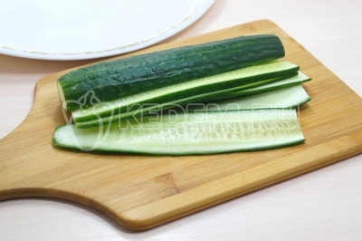 Огурец нарезать тонкими ломтиками в длину.