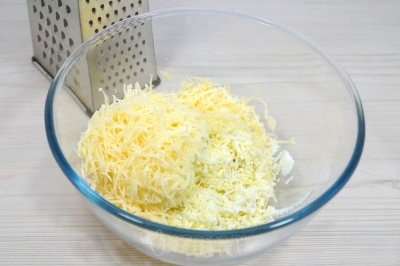 В миску натереть на мелкой терке отварные яйца и 100 грамм любимого твердого сыра.