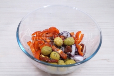 В миске смешать нарезанный лук, кусочки болгарского перца, 100 грамм вяленых томатов и 50 грамм оливок.