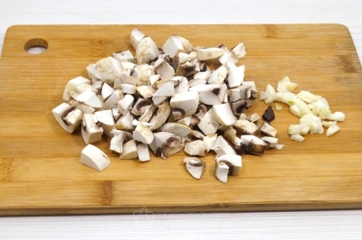 Мелко нарезать 150 грамм свежих шампиньонов и 2 зубчика чеснока.