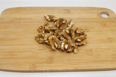 Выложить орехи на доску и нарубить ножом.