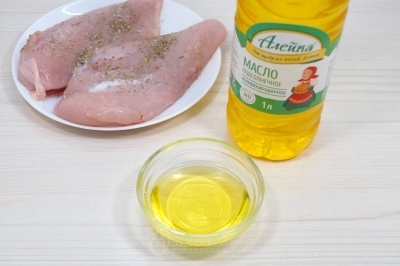 Добавить 3 столовых ложки натурального подсолнечного масла и хорошо смазать куриное филе со всех сторон.