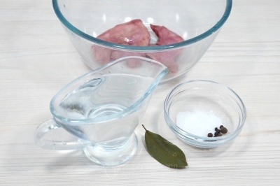 Выложить кусочки печени в большую миску. Добавить 200 миллилитров воды, 1 лавровый лист, 3-4 горошка черного перца и 1/4 чайной ложки соли.