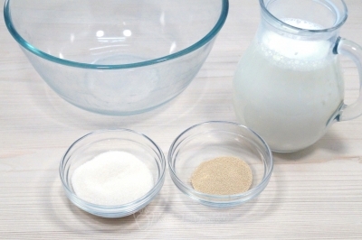 В большой миске смешать 500 миллилитров теплого молока, 5 грамм сухих дрожжей и 2 столовые ложки сахара.